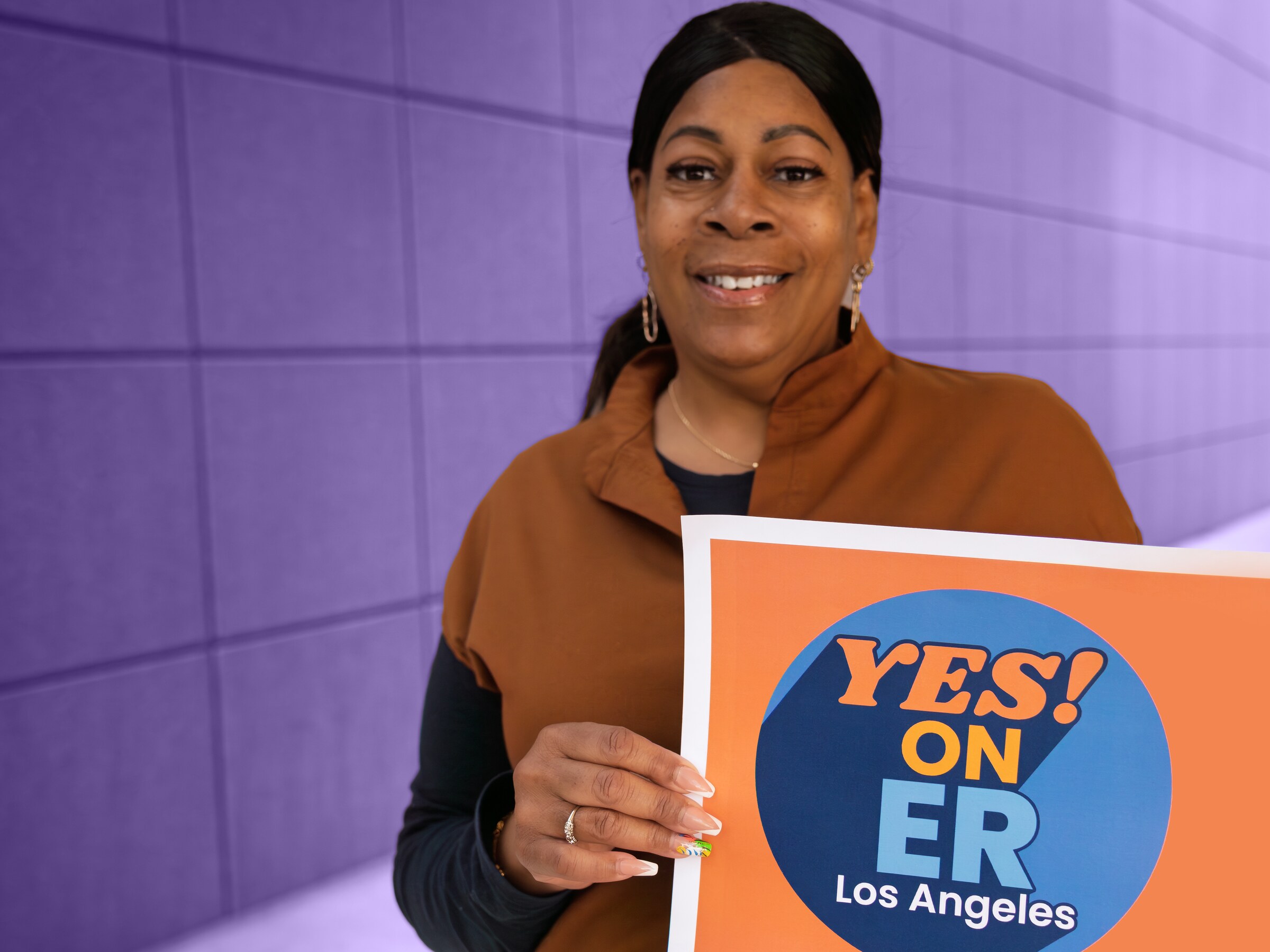 SEIU 721 organizer holding a Yes! On ER sign, photographed in purple duotone