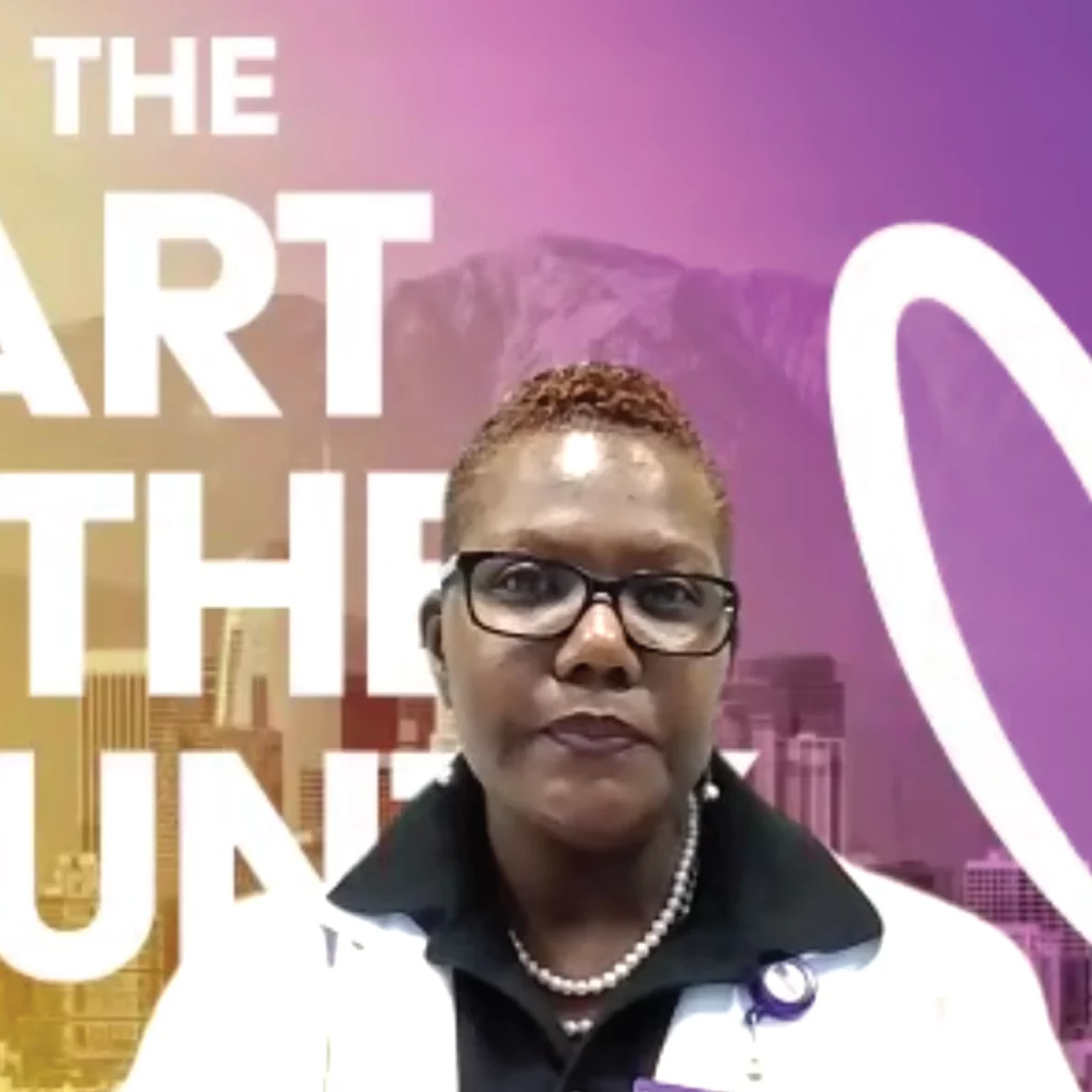 Shamika Mossey appears with a purple zoom background. Shamika is wearing glasses and a white blazer with a black dress shirt.