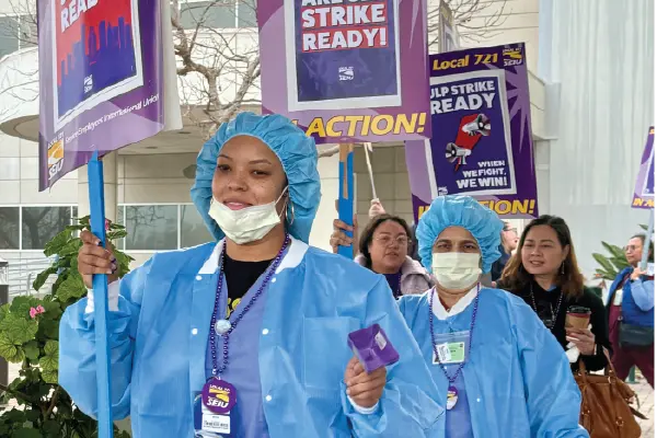 Nurses in blue smocks march outside the Harbor-UCLA Medical Center in Torrance.