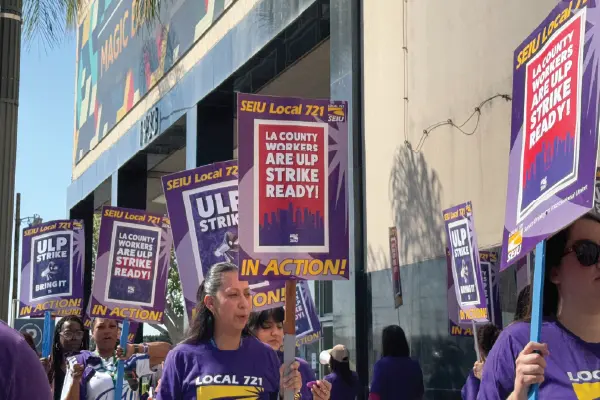 Union members in purple shirts with the SEIU 721 logo on them march outside the Metro North DCFS building in downtown LA.