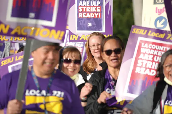 Smiling union workers holding picket signs march outside the Olive View-UCLA Medical Center in Sylmar.