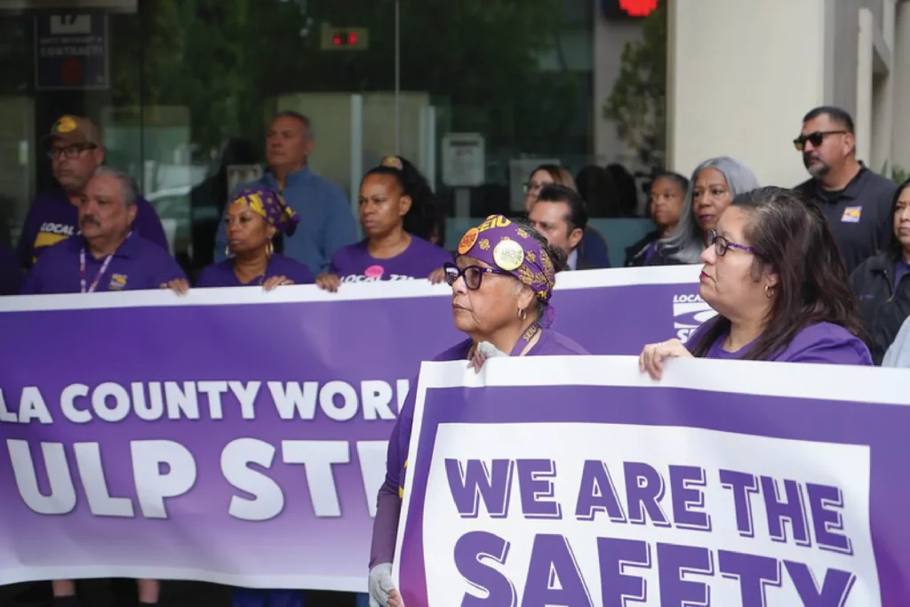 Union members stand together holding banners declaring into to go on a ULP Strike.