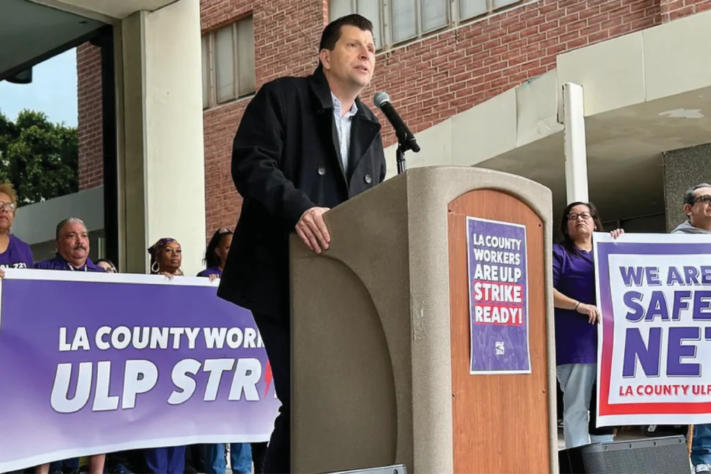Union president surrounded by union members speaks at podium about delivery of ULP Strike 10-Day Notice.