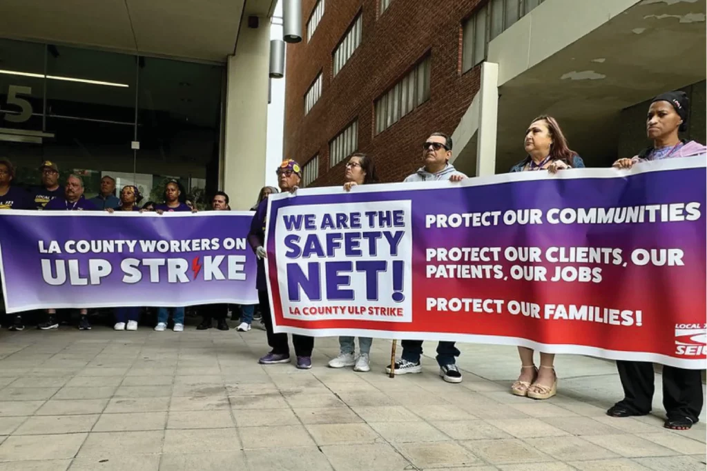 Union members hold two banners expressing intent to go on a ULP strike and describing safety net services they provide.