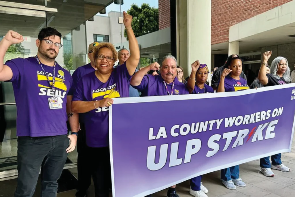 Union members hold their fists in the air as they hold a banner declaring intent to go on a ULP Strike in LA County.