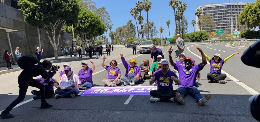 14 union members and community supporters sitting down in the street in a non-violent act of civil disobedience.