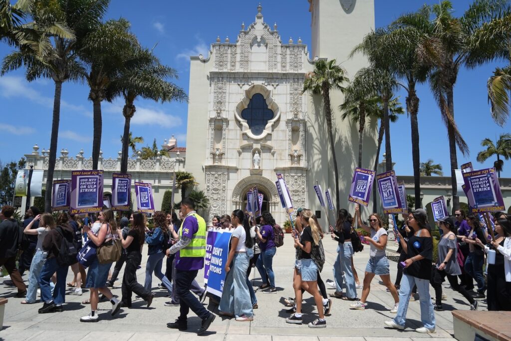 USD NTT Faculty Union members  and students marching past the chapel holding ULP Strike picket signs