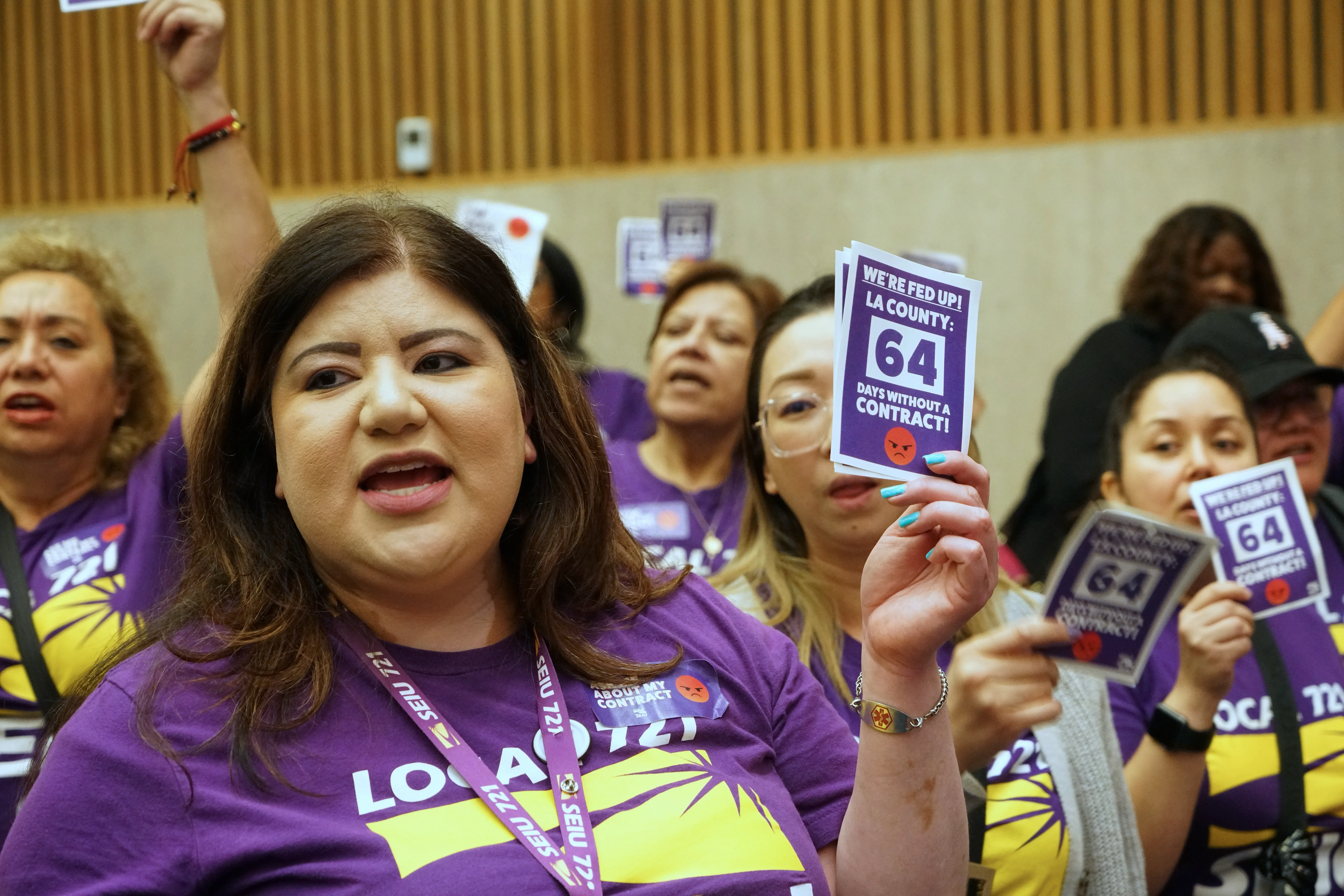 LA County members of SEIU 721 hold aloft signs indicating that they have been working for 64 days without a contract.