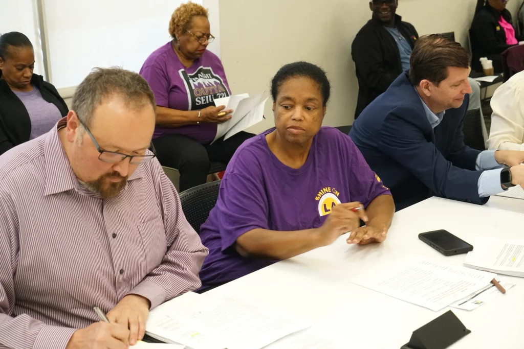 BPC Chair Kelley Dixon-Turner looks on as Ruben Soto signs document.